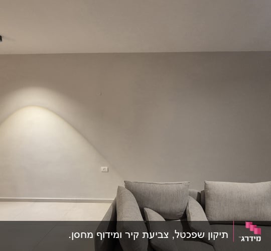 קיר צבוע עם תאורה וספה אפורה